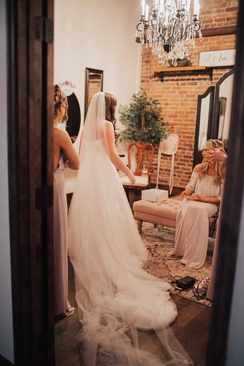 A bride and her friends getting ready beneath a chandelier in The Cotton Loft’s brick-walled suite