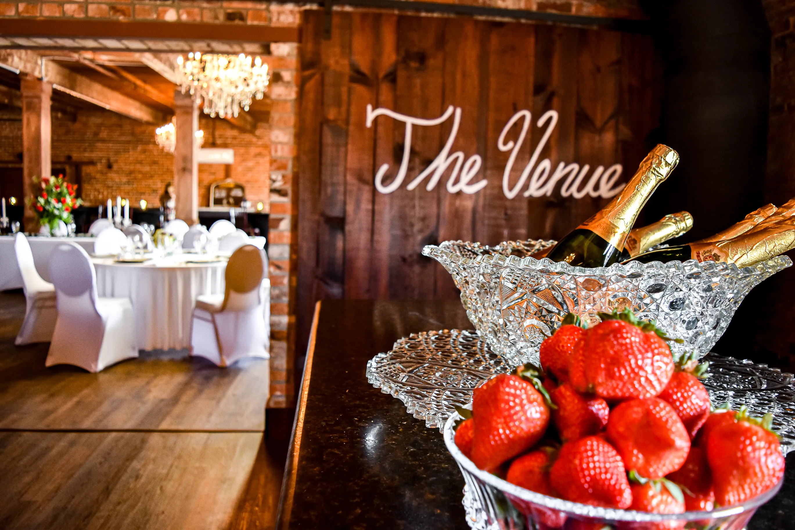 Champagne and strawberries displayed beside The Cotton Loft venue sign