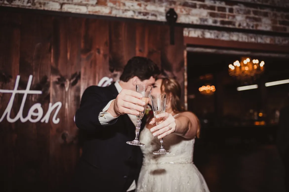 A newly married couple sharing a toast in front of The Cotton Loft’s wooden doors