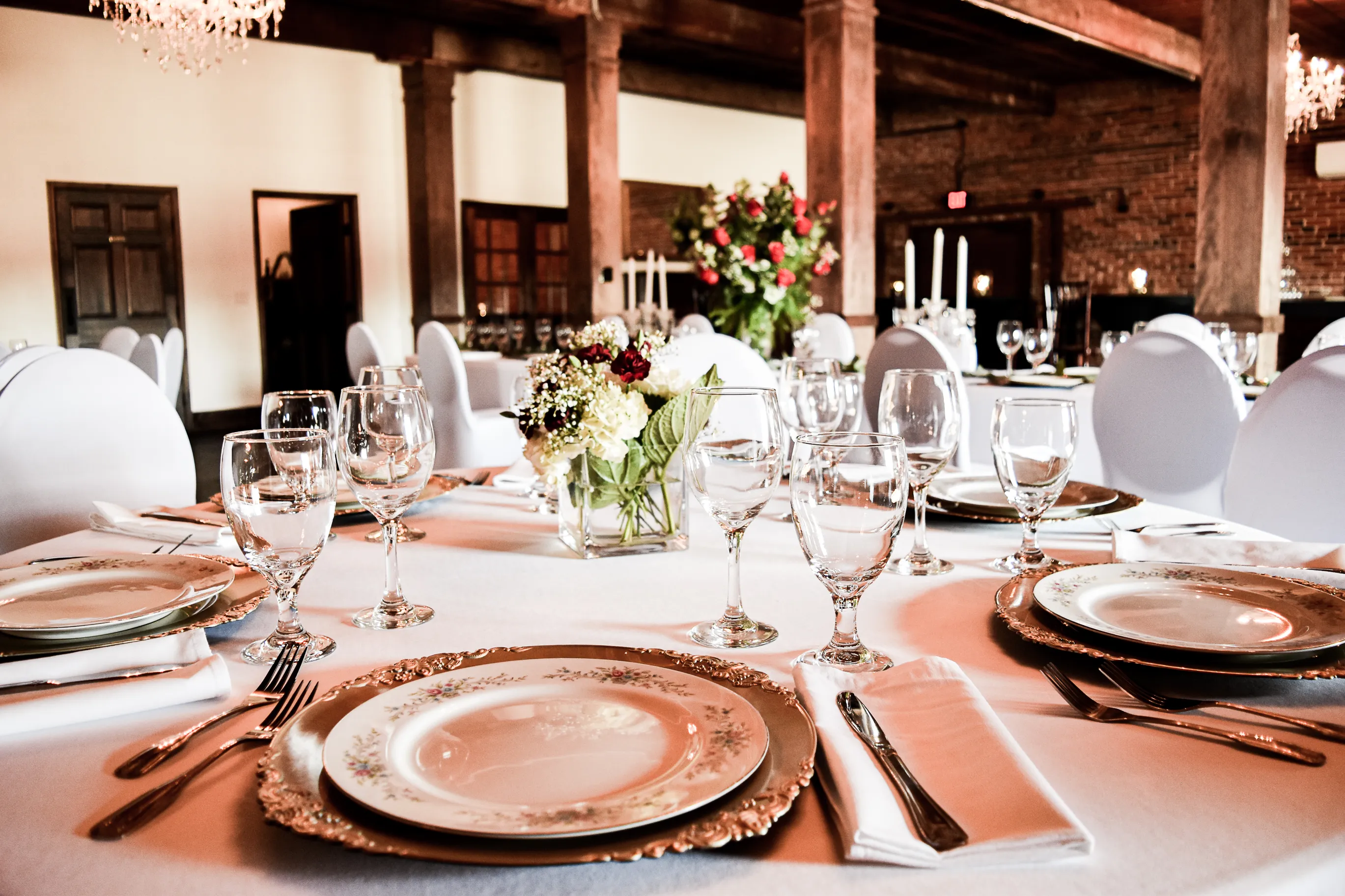 A reception table set with vintage china, glassware, and floral arrangements at The Cotton Loft